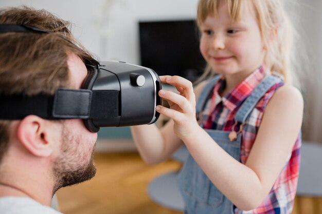 Chica poniendo auriculares VR en el padre