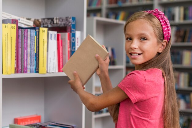 Chica poniendo un libro en el estante