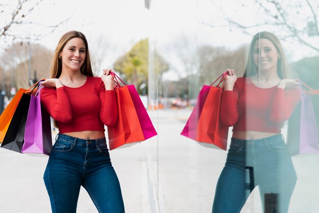 Chica posando para la foto con bolsas de compras