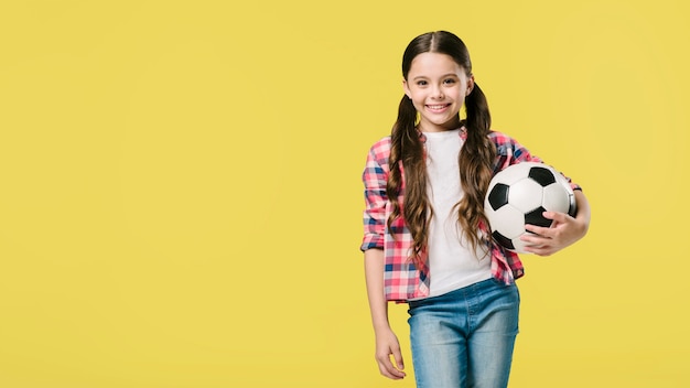 Chica posando con fútbol en estudio