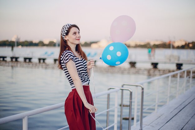 Chica posando con globos en un puerto