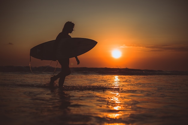 chica posando con una tabla al atardecer