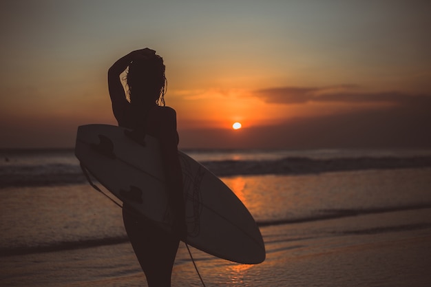 chica posando con una tabla al atardecer