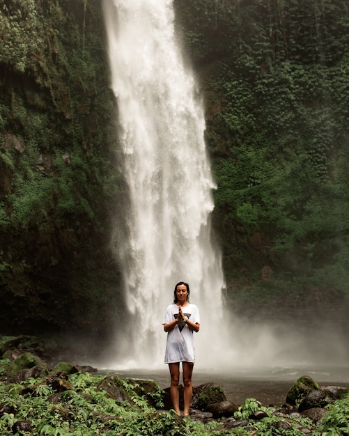 Chica posando con el telón de fondo de una cascada