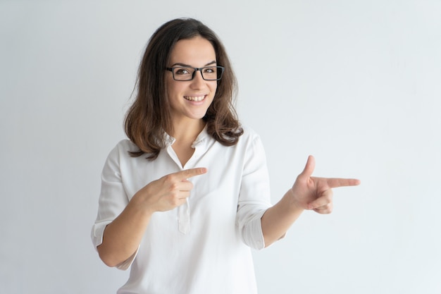 Chica positiva alegre en gafas recomendando nuevo producto o servicio.