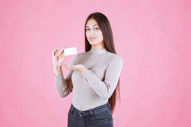 Chica presentando su tarjeta de visita a un socio comercial