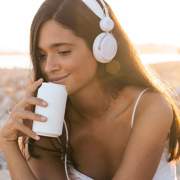 Chica de primer plano con auriculares sosteniendo bebida