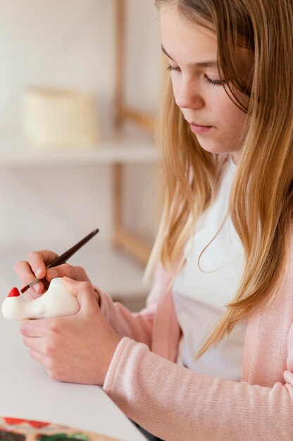 Chica de primer plano pintando en el interior