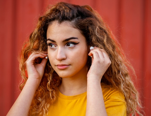 Chica de primer plano poniéndose auriculares