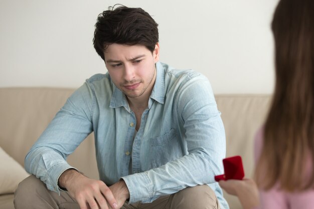 Chica proponiéndose al hombre, chico confundido mirando ceñudo y desconcertado