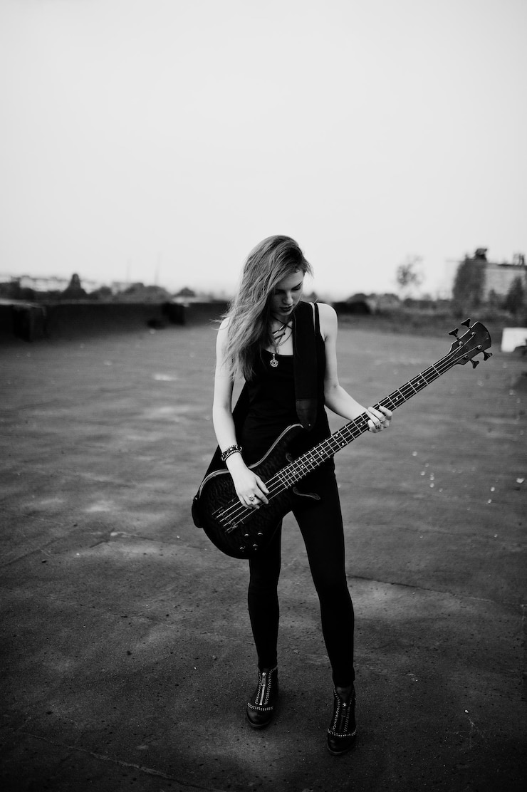 Foto gratuito chica punk pelirroja vestida de negro con bajo en el techo