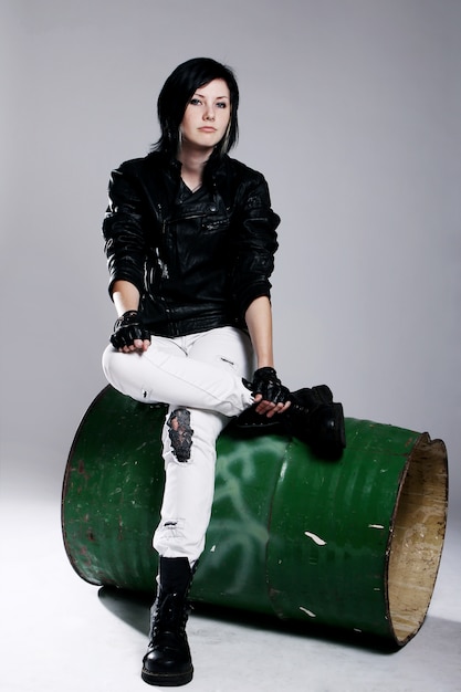 Chica punk sentada en barril de metal