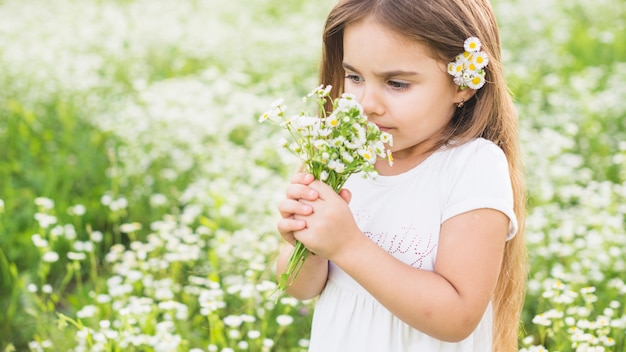Chica que huele a flores silvestres en el prado