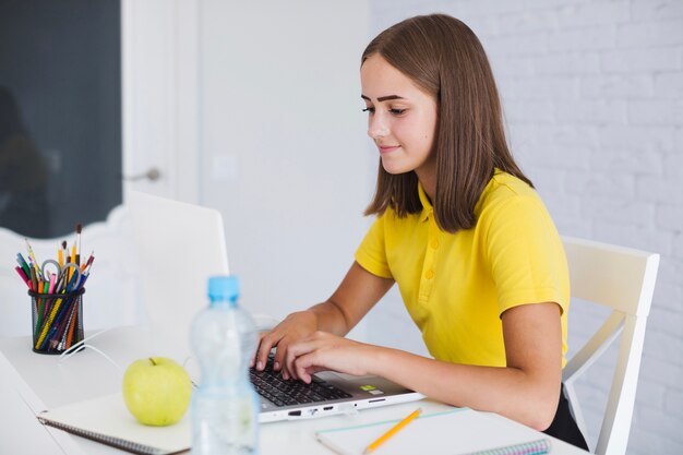 Chica que trabaja con la computadora portátil en la habitación