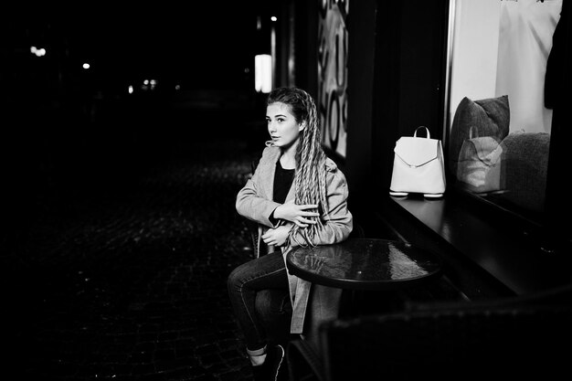 Chica con rastas caminando por la calle nocturna de la ciudad