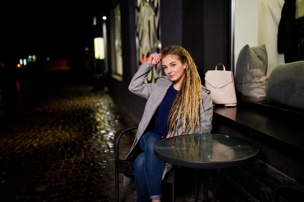 Chica con rastas caminando por la calle nocturna de la ciudad