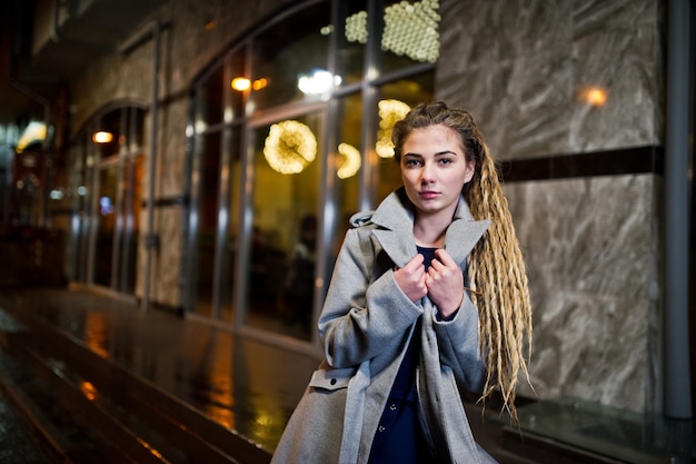 Chica con rastas caminando por la calle nocturna de la ciudad