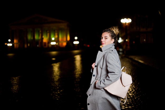 Chica con rastas caminando por la calle nocturna de la ciudad