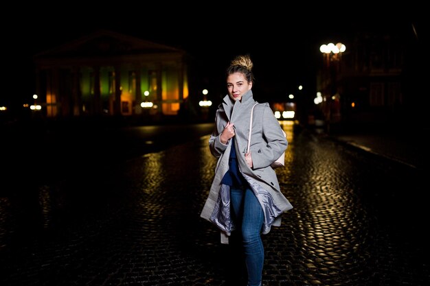 Chica con rastas caminando por la calle nocturna de la ciudad