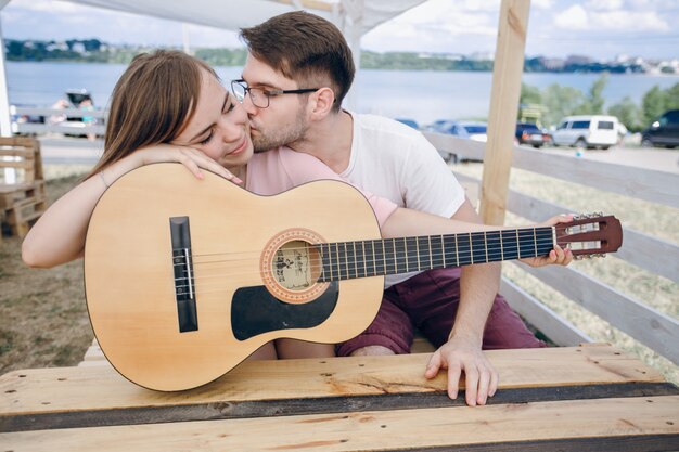 Chica recibiendo un beso mientras toca la guitarra
