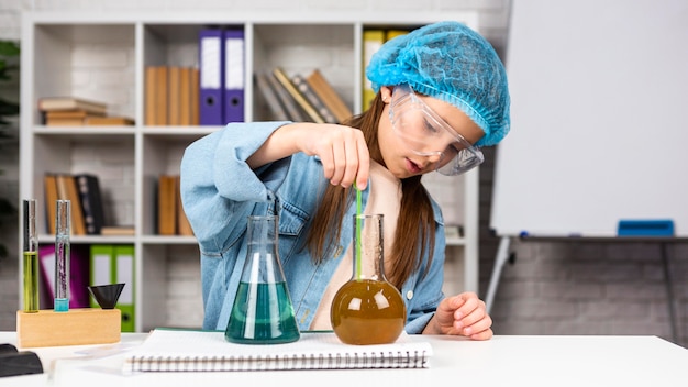 Chica con redecilla haciendo experimentos científicos con tubos de ensayo