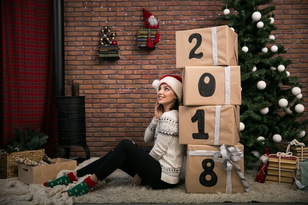 Chica con regalos de Navidad por el árbol de Navidad