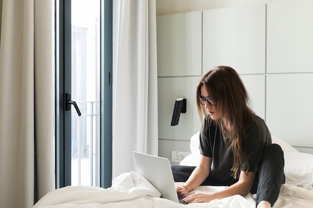 Chica relajada con la computadora portátil en la cama