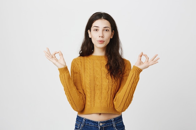 Chica relajada y paciente que muestra un gesto zen, sin pánico, sintiéndose tranquila después de la meditación