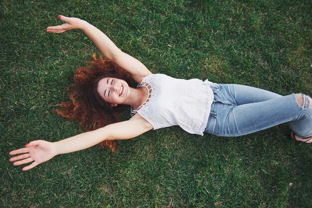 Chica relajante con rojo, tirado en el pasto.