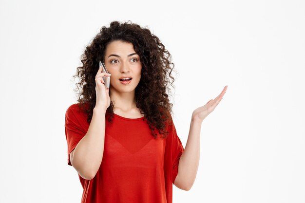 chica rizada confundida hablando por su teléfono