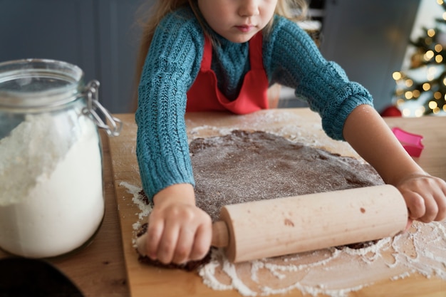 Chica rodando masa de pan de jengibre para galletas caseras