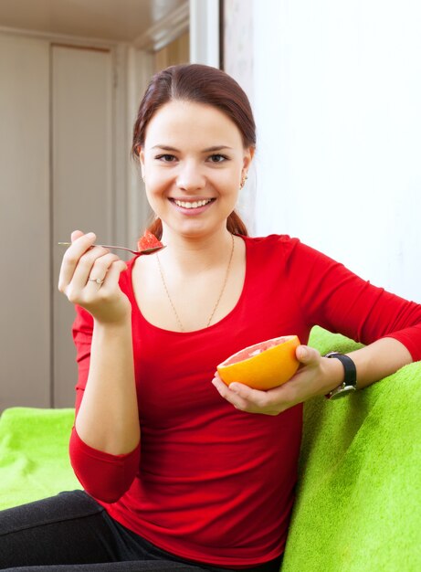 chica en rojo come pomelo en casa