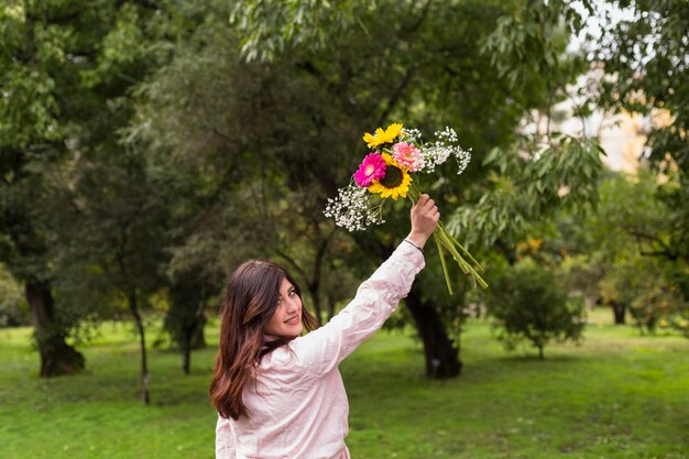 Chica romántica con flores en el parque verde