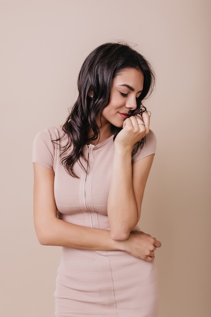 Chica romántica en vestido hermoso gira tímidamente la cabeza. Retrato de morena de muy buen humor