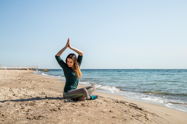 Chica en ropa deportiva fitness junto al mar escuchando