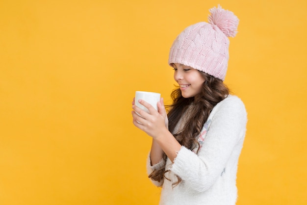 Chica con ropa de invierno y una copa en las manos