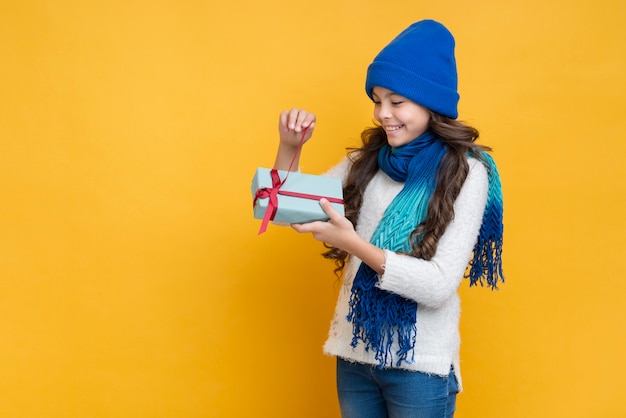 Chica en ropa de invierno desempacando un regalo