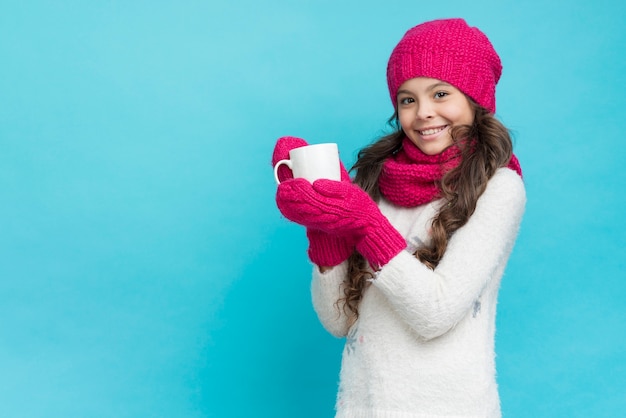 Chica con ropa de invierno y sosteniendo la taza de té