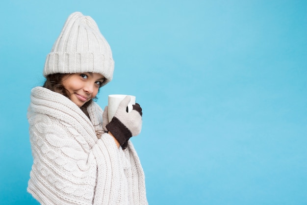 Chica con ropa de invierno y una taza de té.