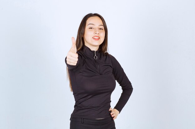 Chica en ropa negra mostrando el pulgar hacia arriba.