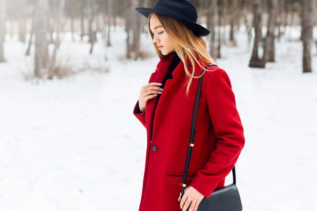 Chica rubia con abrigo rojo en un campo cubierto de nieve