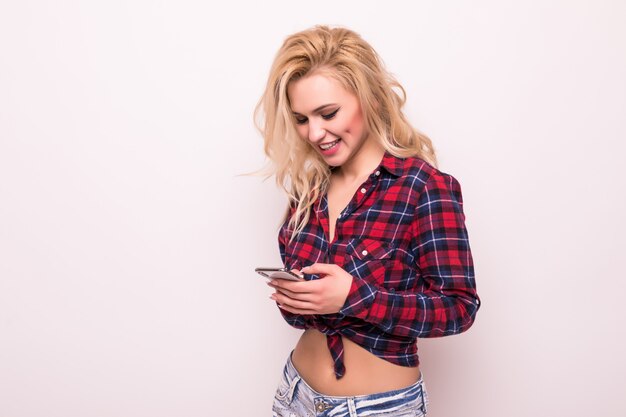 Chica rubia aislada en mensajes de texto blancos en su teléfono y haciendo selfie