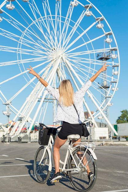 Chica rubia en bicicleta junto a una divertida rueda