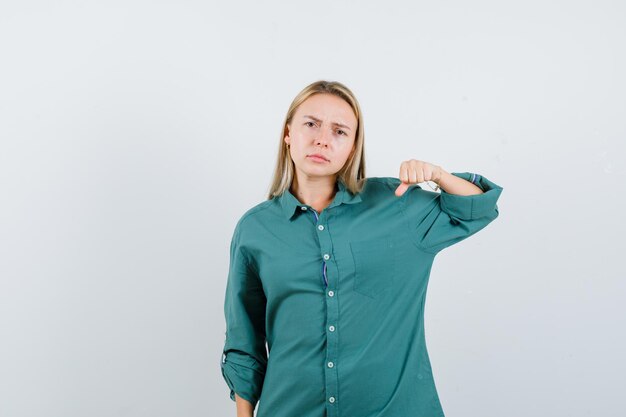 Chica rubia en blusa verde apretando el puño y mirando enojado