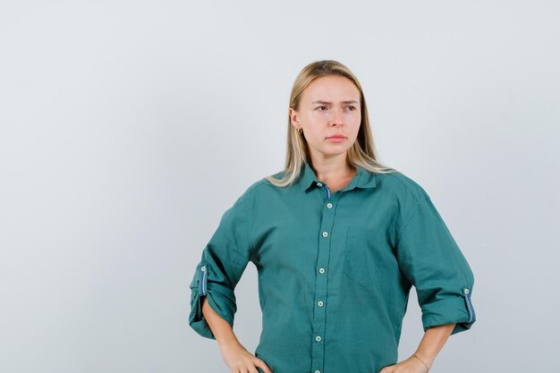 Chica rubia en blusa verde cogidos de la mano en la cintura y mirando pensativo