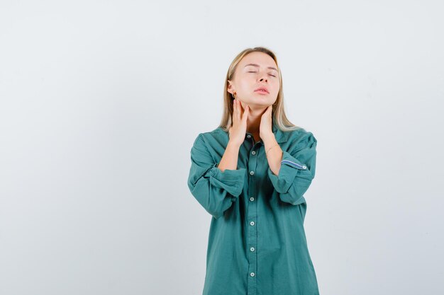 Chica rubia cogidos de la mano en el cuello mientras cierra los ojos en una blusa verde y parece tranquilo