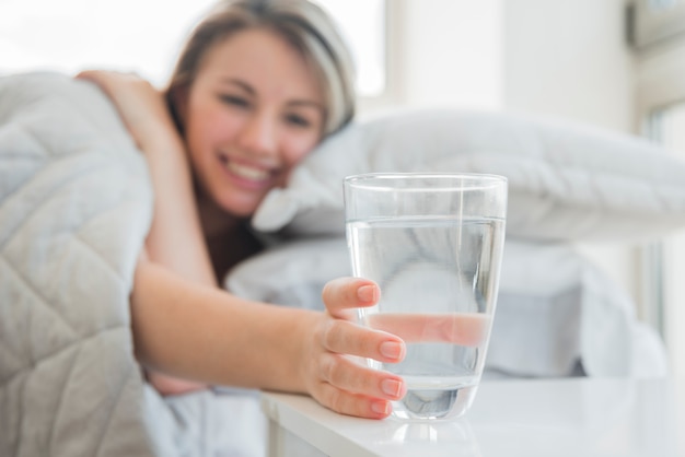 Chica rubia cogiendo vaso de agua