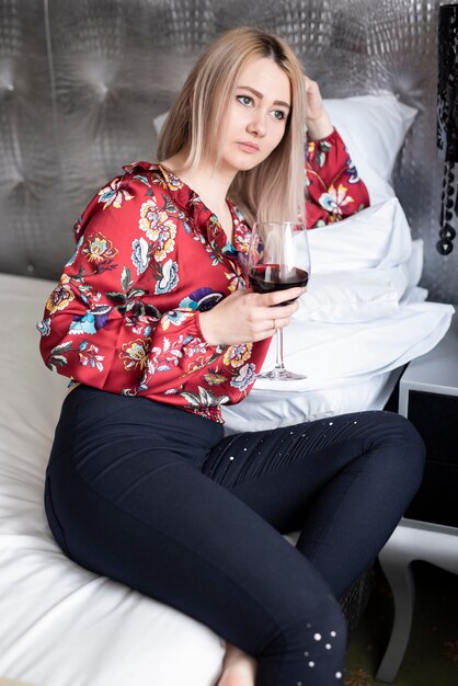 Chica rubia con una copa de vino mirando a otro lado