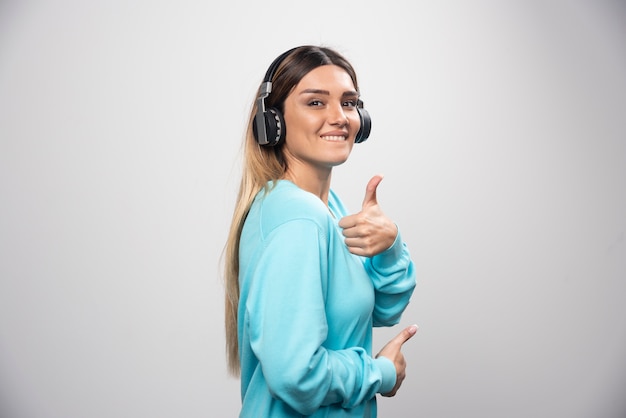 Chica rubia dj escuchando música en auriculares y divirtiéndose.