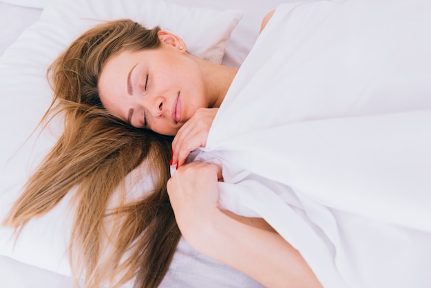 Chica rubia durmiendo en la cama